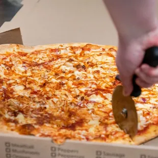 a person cutting a pizza in a box