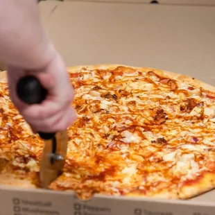 a person cutting a pizza in a box