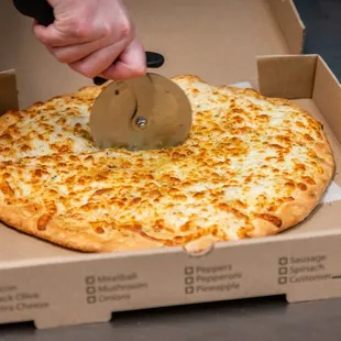 a person cutting a pizza in a box