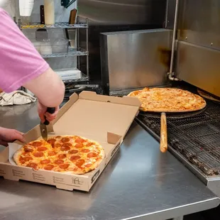 a person cutting a pepperoni pizza