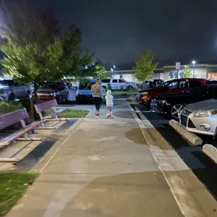 a woman walking down a sidewalk at night
