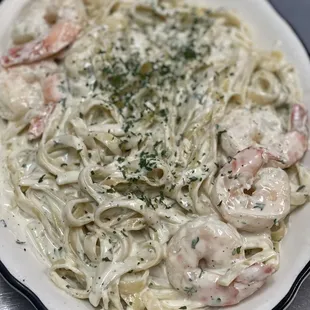 a plate of pasta with shrimp and parmesan cheese