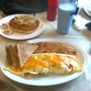 Unidentified omelet with hashbrowns and toast; single pancake topped with apples; glass of milk.  Quite yummy!