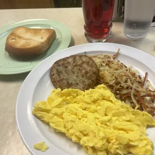 Three scrambled eggs, sausage patty and hash browns with gluten free bread.