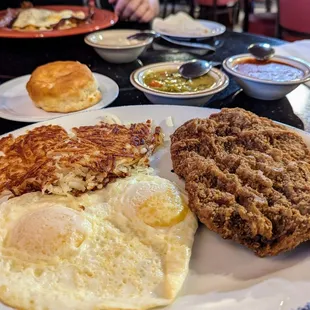 Chicken fried steak and eggs with both red and green chiles on the side