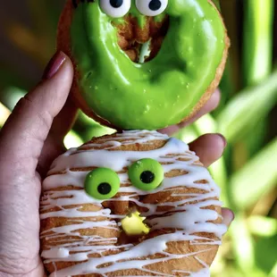 a hand holding a donut with eyes and eyes on it