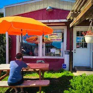 a man sitting at a picnic table under an umbrella