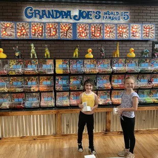 two girls standing in front of a display of candy