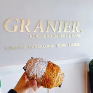 a hand holding a croissant