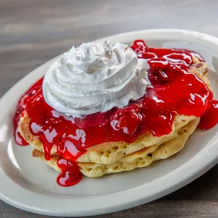 a stack of pancakes topped with whipped cream and jelly