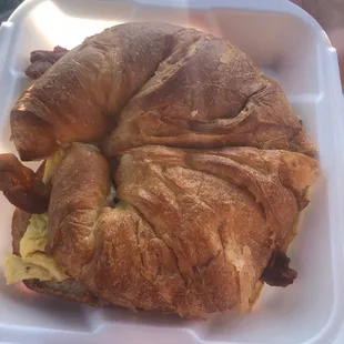 a croissant sandwich in a styrofoam container