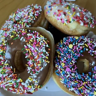 a plate of donuts with chocolate frosting and sprinkles