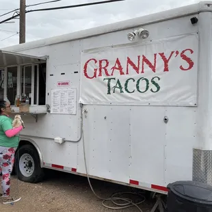 a woman standing in front of a food truck