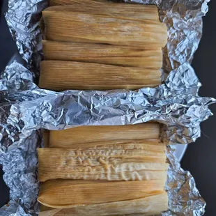 two tamales wrapped in aluminum foil