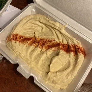 a container of hummus and a container of broccoli