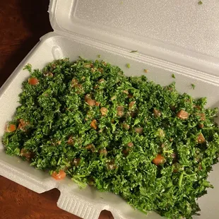 a takeout container with a salad in it