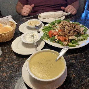 a man sitting at a table with a bowl of soup and a plate of salad