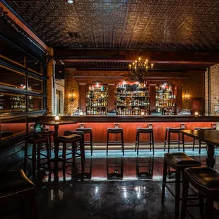 a dimly lit bar with wooden bar stools