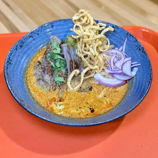 Kao Soi - Egg noodles in aromatic curry broth, red onion, pickle mustard, lime wedge, and chili oil with beef