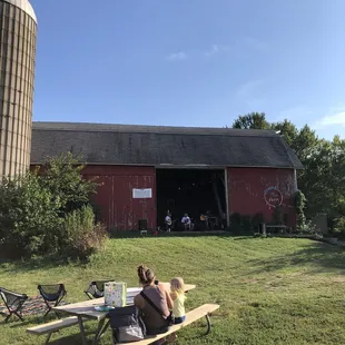 two people sitting at a picnic table in front of a red barn