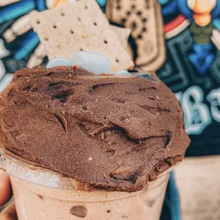 a hand holding a cup of chocolate ice cream