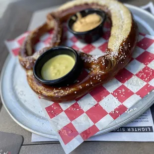 a large pretzel on a plate with dipping sauces