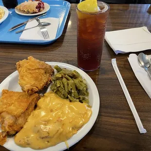 My plate of fried chicken, cheesy au gratin potatoes and green beans. My husband&apos;s meal is in the background.