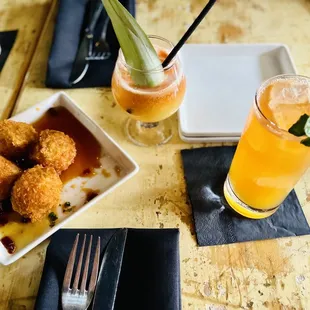 a plate of fried meatballs and a glass of orange juice