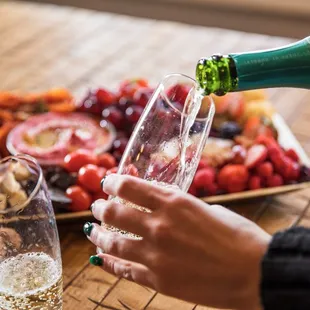 a person pouring champagne into a glass