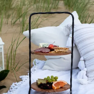 three tiered trays of food on a beach