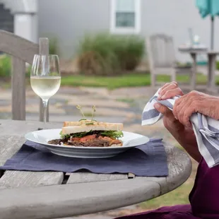 a woman sitting at a table with a plate of food and a glass of wine