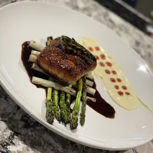 a plate of food with asparagus and sauce
