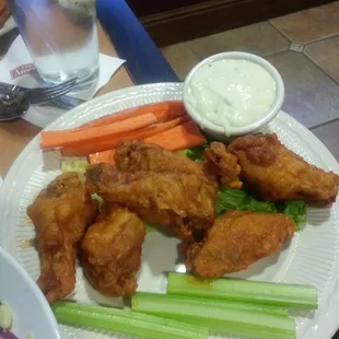 a plate of chicken wings, carrots and celery
