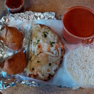 Butter chicken, rice, garlic naan, and vegetarian samosas.
