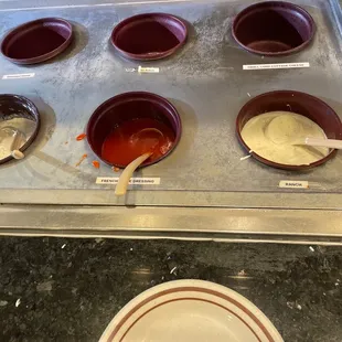 a tray of muffins and bowls of sauce