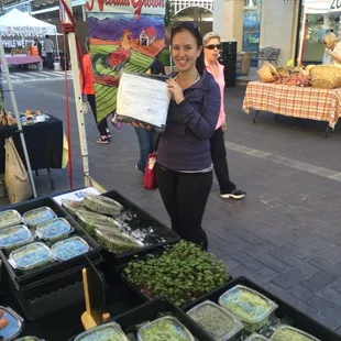 a woman standing in front of a farmers market