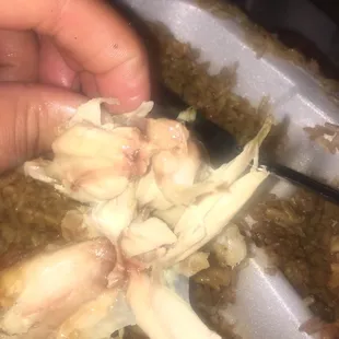 a person's hand holding a spoon and scooping garlic into a dish