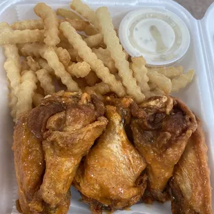  chicken wings and french fries in a styrofoam container