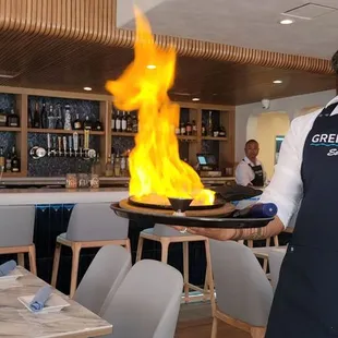 Saganaki Pan seared kasseri cheese, flambéed in brandy tableside, served with pita priced at $17.00.