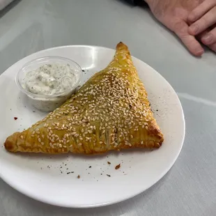 a white plate with a pastry and dip