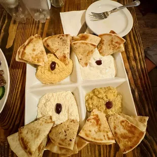 a tray of pita chips, hummus, and olives