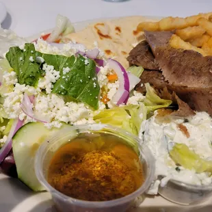 a plate of food with meat, salad, and french fries