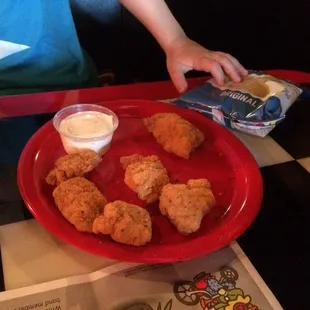 Chicken nugget kids meal with chips and ranch dipping sauce.