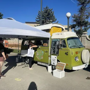 a woman standing in front of a green bus