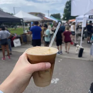 a hand holding a cup of iced coffee