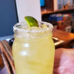 a hand holding a jar of limeade