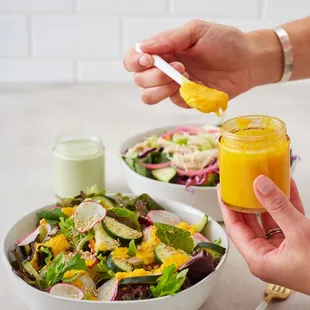  hand holding a spoon over a bowl of salad