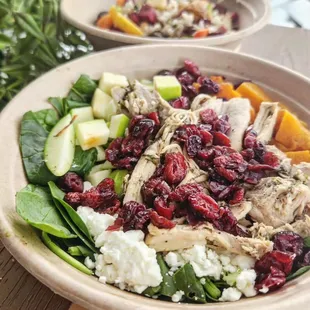 two bowls of salad with chicken and cranberries