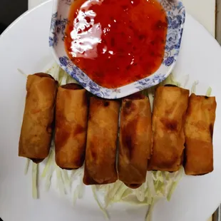 a plate of spring rolls and a bowl of sauce