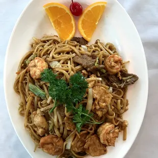 a plate of noodles with shrimp and vegetables